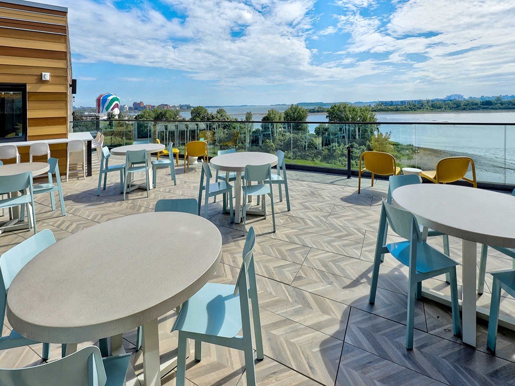 a patio with tables and chairs overlooking the water